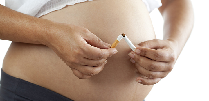 A pregnant woman snaps a cigarette in half