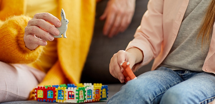 childminder and child playing with toys on a sofa